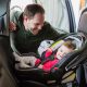 A father safely buckles his daughter into her rear facing car seat. (Credit: North Dakota DOT)